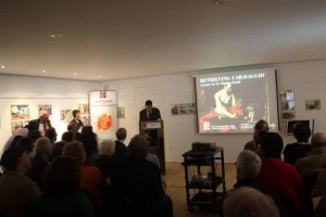 Picture shows an audience, a podium and a projector screen. The screen says "Retrieving Caravaggio lecture by Dr. Marius Zerafa."